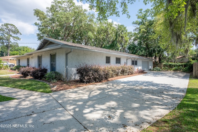 ranch-style home featuring stucco siding, concrete driveway, and an attached garage