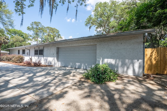 view of property exterior with stucco siding, fence, driveway, and an attached garage