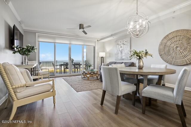 dining space with wood finished floors, ornamental molding, a ceiling fan, and a chandelier