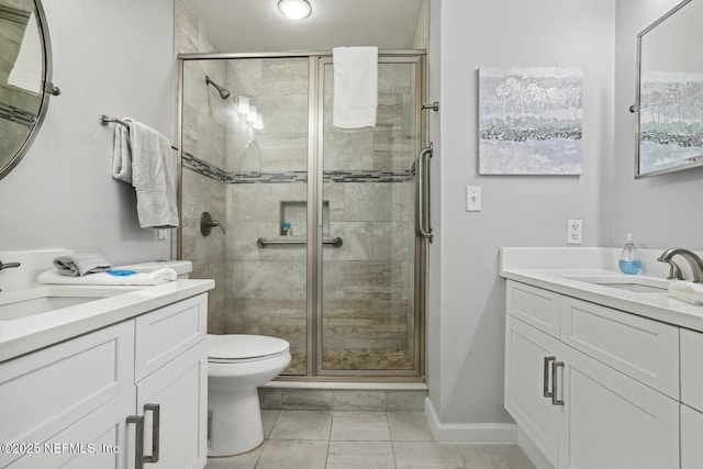 full bathroom featuring a stall shower, two vanities, toilet, and baseboards