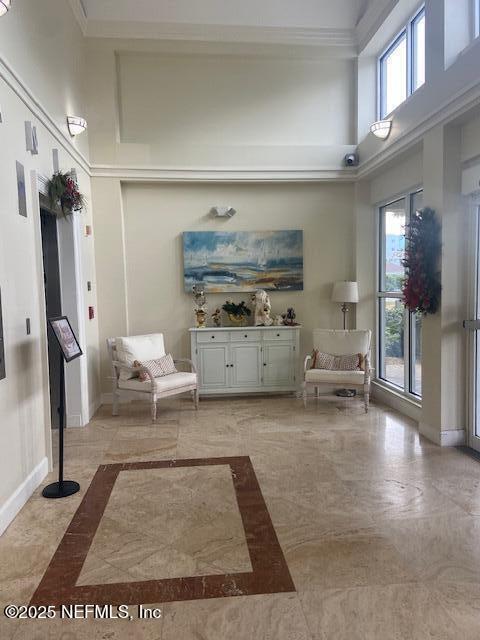 living room with a towering ceiling, baseboards, and crown molding