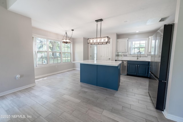 kitchen featuring an inviting chandelier, a sink, stainless steel appliances, a center island, and light countertops
