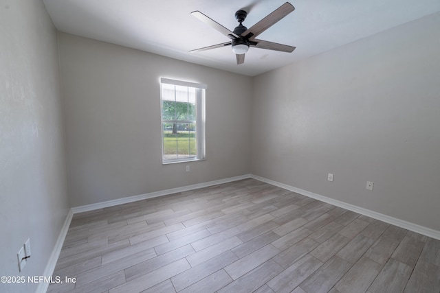empty room with ceiling fan, light wood finished floors, and baseboards