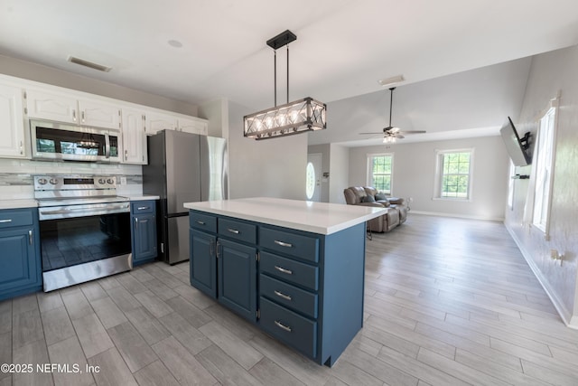 kitchen featuring appliances with stainless steel finishes, blue cabinetry, light wood-type flooring, and white cabinets