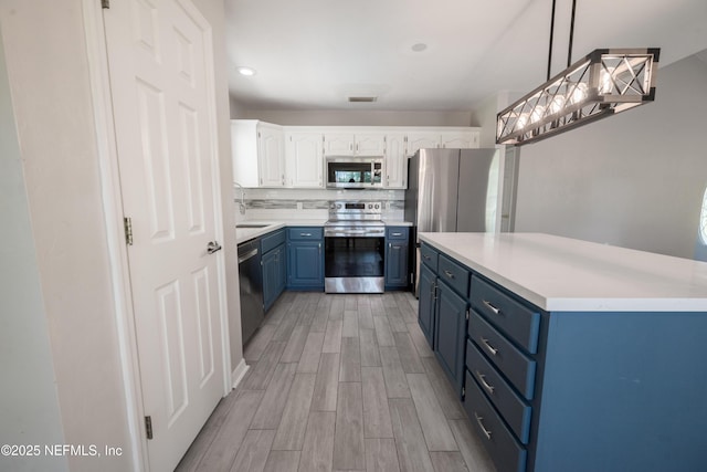 kitchen featuring white cabinets, light wood-style flooring, a sink, stainless steel appliances, and blue cabinetry