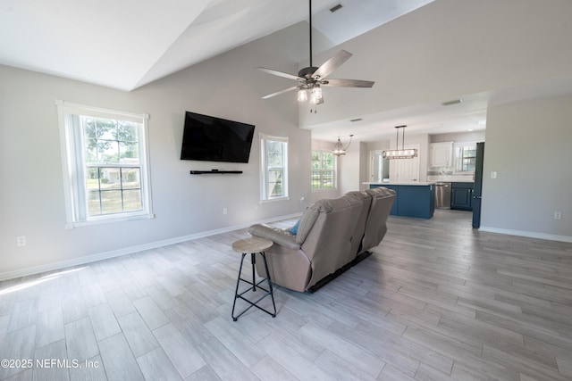 living room with a healthy amount of sunlight, light wood-type flooring, ceiling fan with notable chandelier, and lofted ceiling