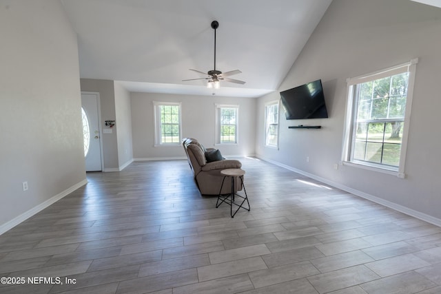 living area with baseboards, wood finished floors, ceiling fan, and vaulted ceiling