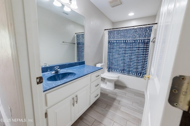 bathroom featuring toilet, wood finish floors, shower / tub combo, and vanity