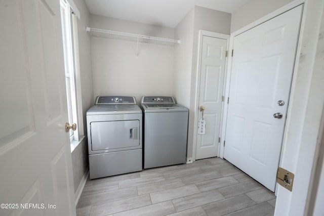 clothes washing area with independent washer and dryer, light wood finished floors, and laundry area