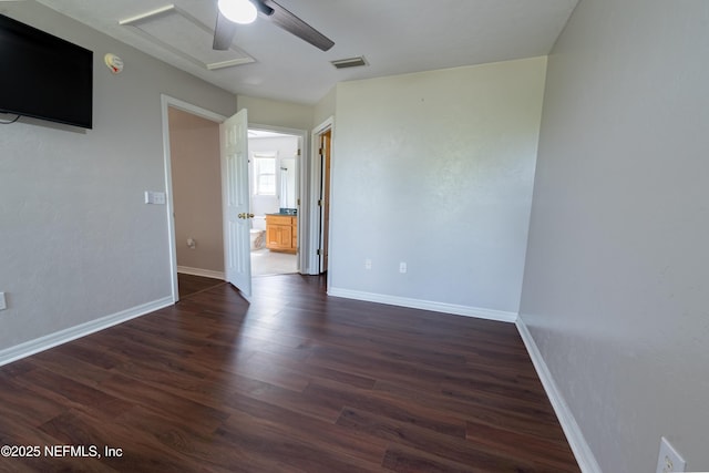 spare room featuring attic access, visible vents, baseboards, and dark wood finished floors