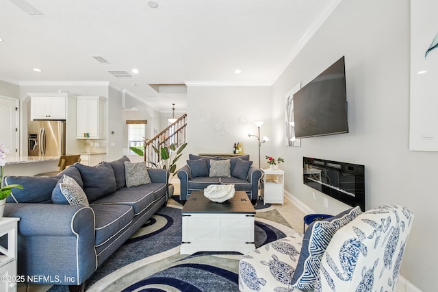 living room featuring baseboards, ornamental molding, and stairs