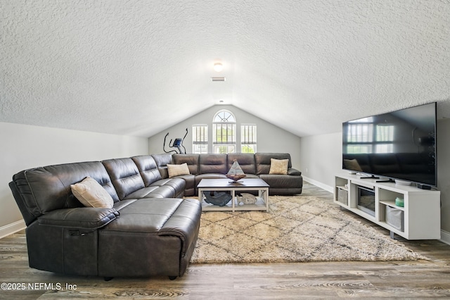 living room with a textured ceiling, baseboards, vaulted ceiling, and wood finished floors