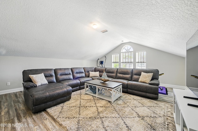 living area with baseboards, a textured ceiling, lofted ceiling, and wood finished floors