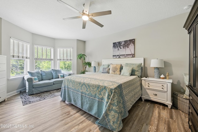 bedroom featuring baseboards, ceiling fan, and dark wood-style floors