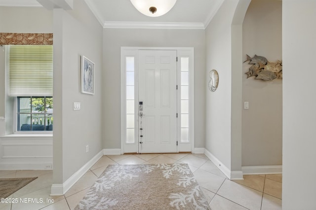 entryway with crown molding, arched walkways, baseboards, and light tile patterned floors