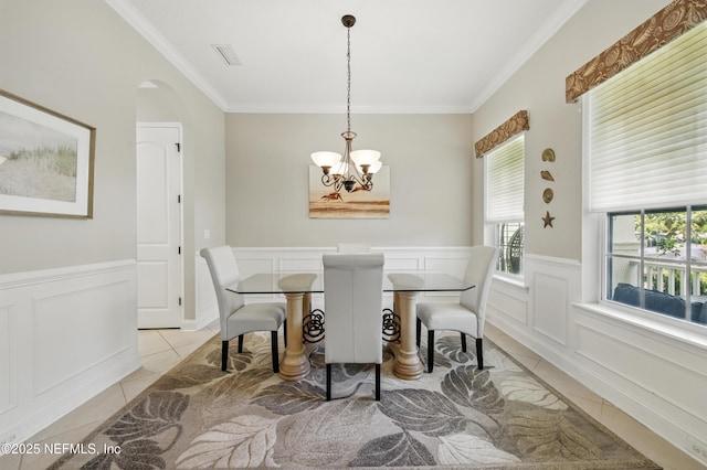 dining space featuring light tile patterned floors, crown molding, visible vents, and a notable chandelier