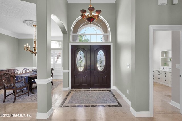 foyer entrance with arched walkways, baseboards, a notable chandelier, and a towering ceiling