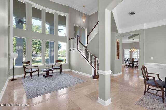 interior space with visible vents, ornamental molding, ceiling fan with notable chandelier, and arched walkways