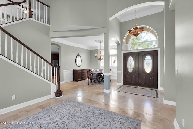 foyer featuring crown molding, stairs, a high ceiling, and a notable chandelier