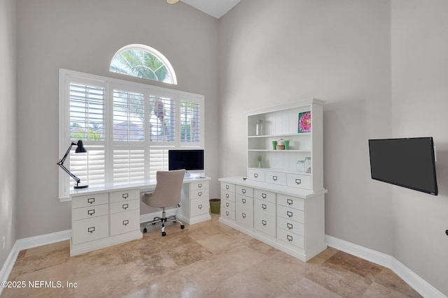 home office featuring baseboards and a towering ceiling