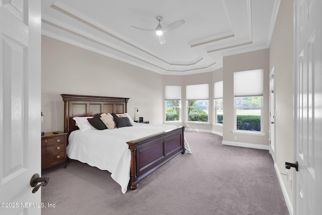 carpeted bedroom featuring crown molding, baseboards, a ceiling fan, and a tray ceiling