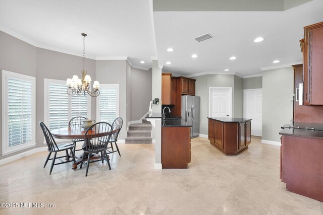 kitchen featuring recessed lighting, a kitchen island, stainless steel refrigerator with ice dispenser, visible vents, and ornamental molding