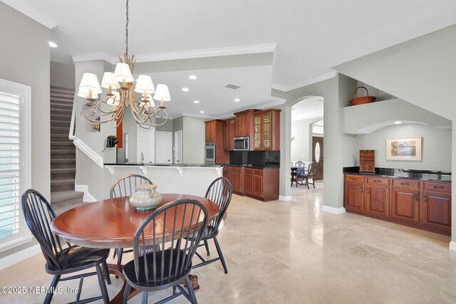 dining room featuring arched walkways, a chandelier, baseboards, ornamental molding, and stairway