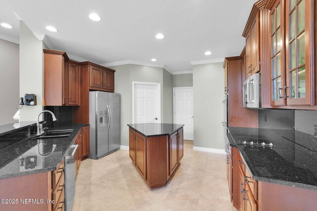 kitchen featuring appliances with stainless steel finishes, a center island, a sink, baseboards, and ornamental molding