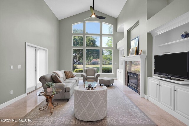 living room featuring light tile patterned flooring, baseboards, ceiling fan, high vaulted ceiling, and a premium fireplace