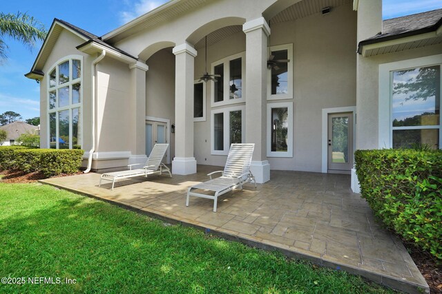 back of house featuring a lawn, french doors, a patio area, and stucco siding