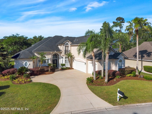 french country inspired facade featuring an attached garage, stucco siding, concrete driveway, and a front yard