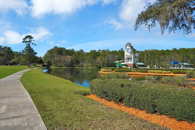 view of property's community with a lawn, a water view, and a forest view