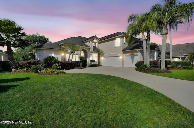 view of front facade featuring a yard, driveway, and stucco siding