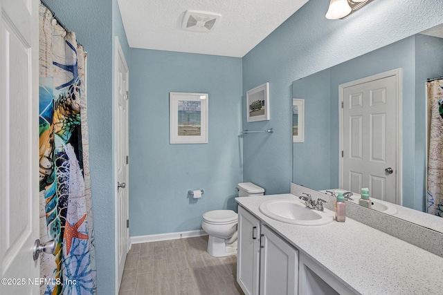 full bathroom with vanity, wood finished floors, toilet, baseboards, and a textured ceiling