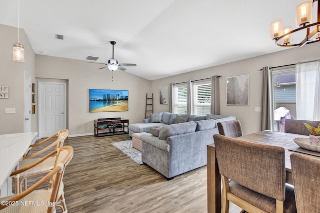 living room with visible vents, light wood finished floors, ceiling fan with notable chandelier, and lofted ceiling