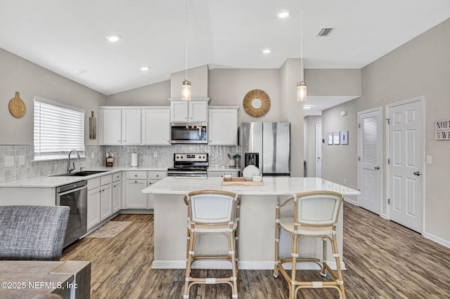 kitchen featuring wood finished floors, stainless steel appliances, a sink, and a center island
