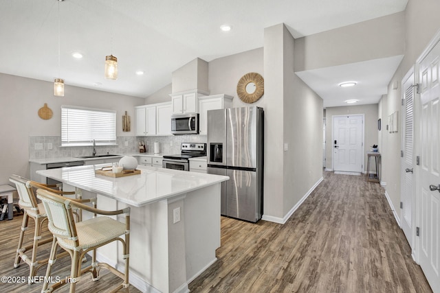 kitchen featuring a sink, stainless steel appliances, decorative backsplash, a kitchen island, and vaulted ceiling