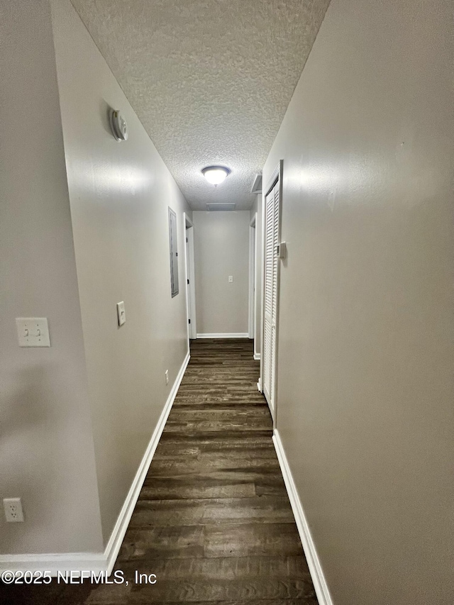 hall with a textured ceiling, baseboards, and wood finished floors