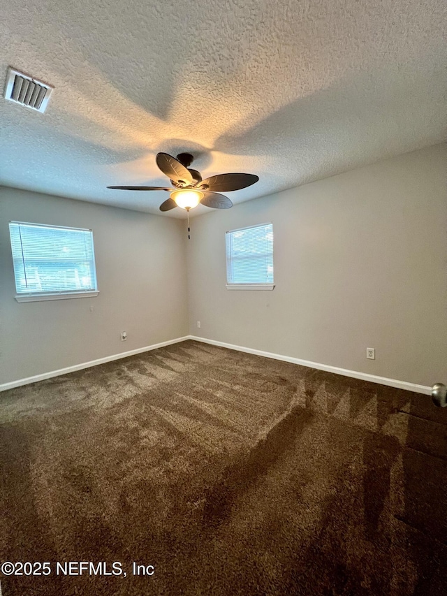 carpeted spare room featuring baseboards, a ceiling fan, a textured ceiling, and visible vents