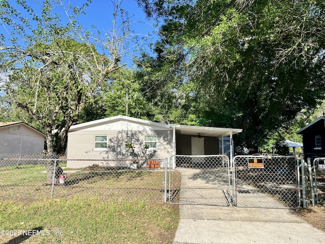 manufactured / mobile home with driveway, a fenced front yard, and a gate