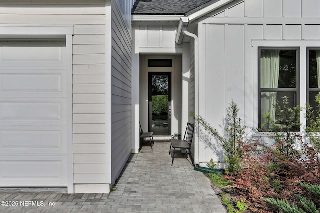 view of exterior entry featuring board and batten siding and roof with shingles