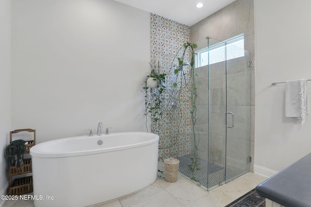full bath featuring baseboards, a freestanding tub, a shower stall, and recessed lighting