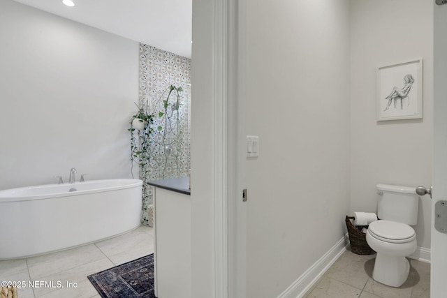 bathroom featuring toilet, a soaking tub, tile patterned flooring, and baseboards