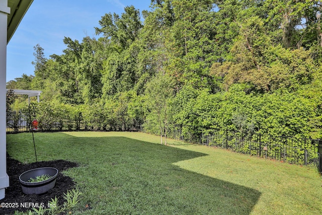 view of yard with a wooded view and fence