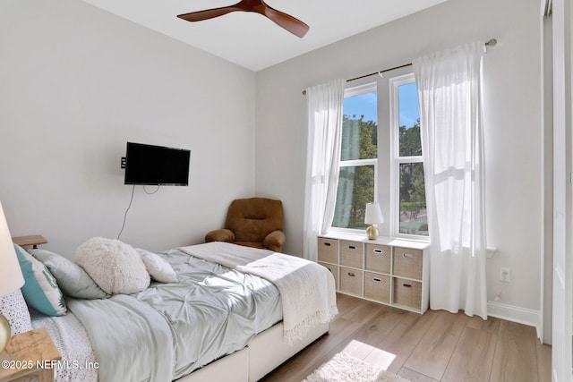 bedroom with a ceiling fan, light wood-style flooring, and baseboards