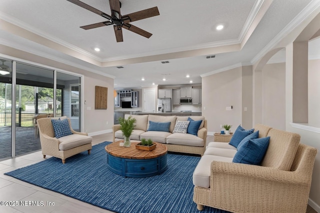 64 Nevis Peak Ln, Saint Augustine, FL 32092 - living room featuring a ceiling fan, a tray ceiling, crown molding, arched walkways, and recessed lighting