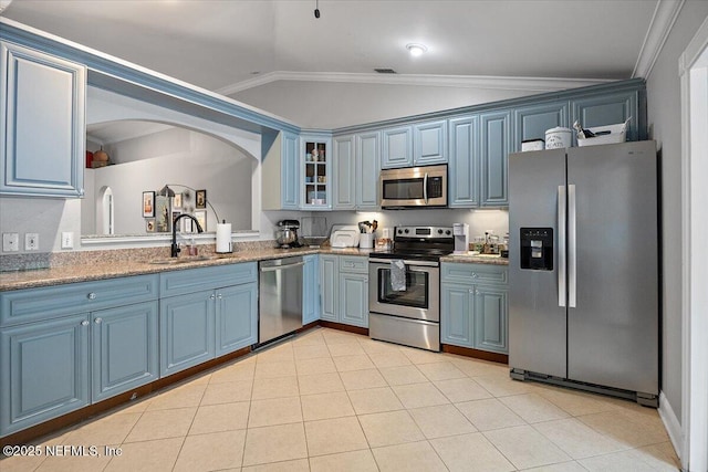2681 Kimberly Forest Dr E, Jacksonville, FL 32246 - kitchen with stainless steel appliances, lofted ceiling, a sink, blue cabinetry, and glass insert cabinets