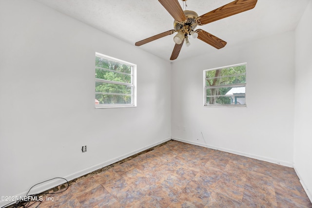 empty room with ceiling fan and baseboards