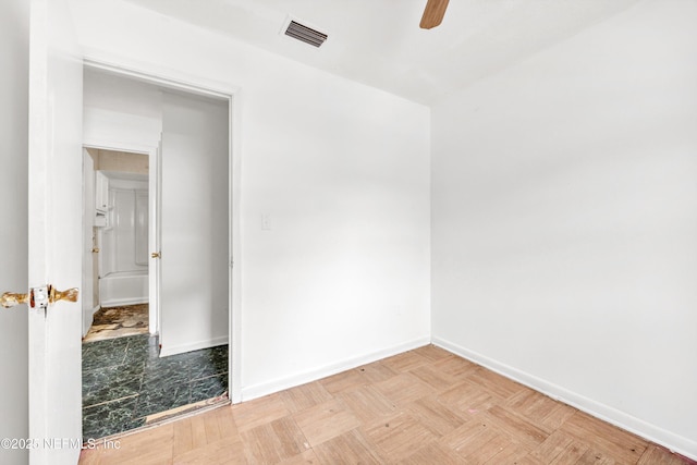 unfurnished room featuring visible vents, a ceiling fan, and baseboards