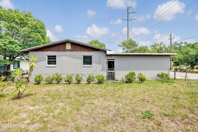 back of property featuring fence and a yard